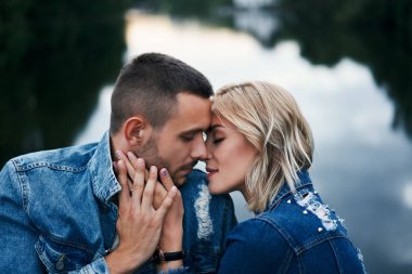 Genç çift göl kenarında birbirine dokunuyor.