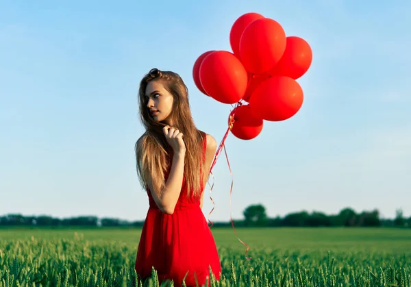 Młoda Kobieta Pozowanie Czerwonymi Balonami Słonecznym Polu — Zdjęcie stockowe