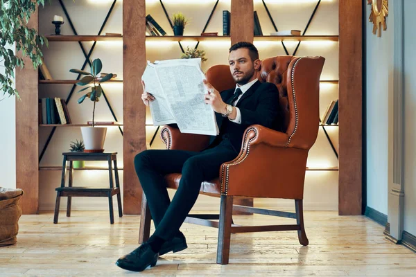 在现代内陆 年轻的商人早上坐在扶手椅上 自信地阅读报纸和最新消息 — 图库照片
