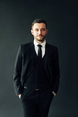 Siyah arka planda şık takım elbiseli genç bir adamın portresi.