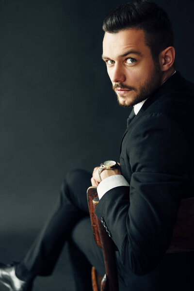 Portrait of elegant young man in suit on black background