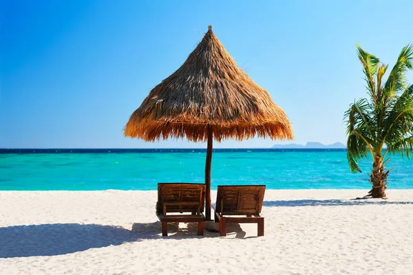 Hermosa playa tropical con dos tumbonas y sombrilla de paja — Foto de Stock