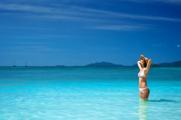 Sommardrömmar. Vacker sexig kvinna i vit bikini och halmhatt koppla av i turkost havsvatten på tropisk strand — Stockfoto