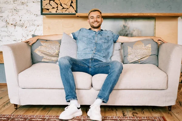 Guapo sonriente hombre relajarse en el sofá en casa —  Fotos de Stock