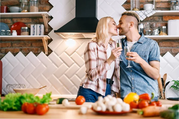 Fiatal boldog pár pezsgőzik és élvezik egymás társaságát otthon a konyhában. — Stock Fotó