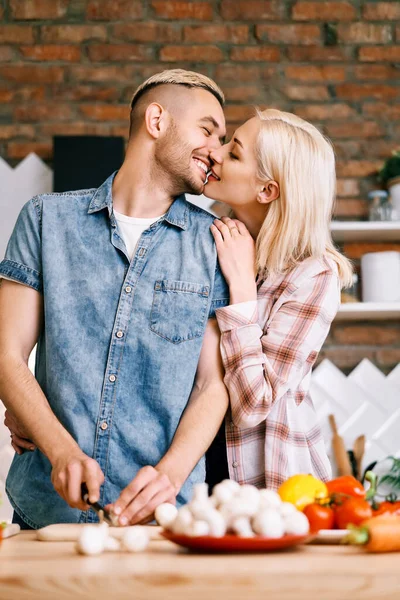 Unga par kyssas och matlagning tillsammans vegetarisk mat i köket hemma — Stockfoto