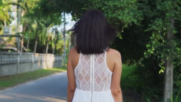 Jovem mulher de vestido branco andando na estrada na ilha tropical — Vídeo de Stock