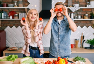 Mutlu gülümseyen çift mutfakta birlikte yemek pişiriyor.