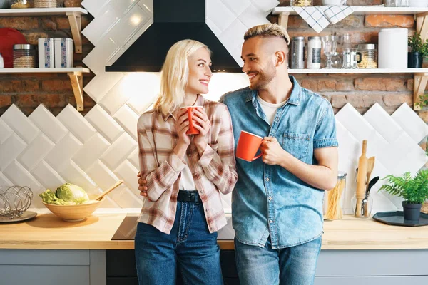 Joven pareja feliz beber café por la mañana y disfrutar de la compañía de los demás en la cocina en casa —  Fotos de Stock