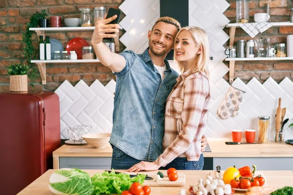 Jeune couple heureux prendre selfie à leur cuisine — Photo
