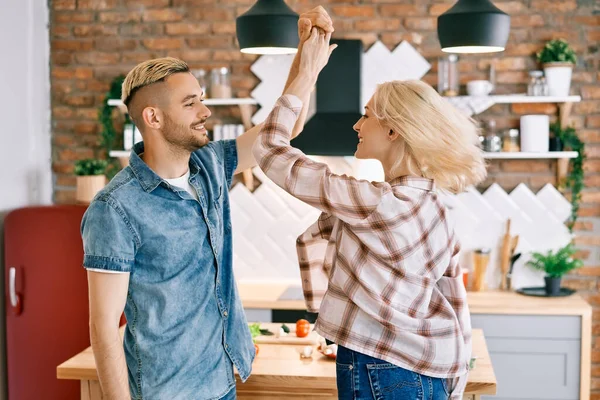 Feliz joven pareja enamorada bailando en la cocina en casa y divirtiéndose —  Fotos de Stock