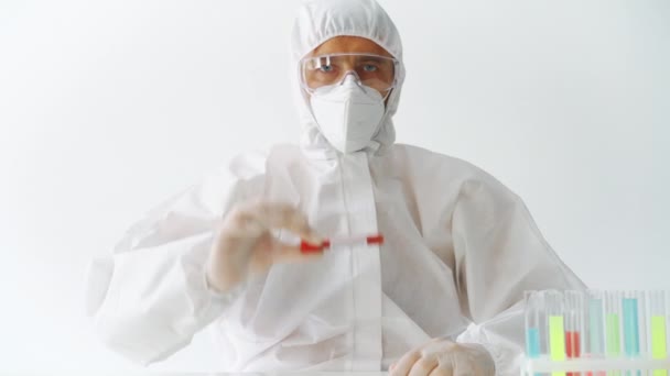 Врач в защитном костюме показывает коронавирус, инфицированный пробиркой крови — стоковое видео