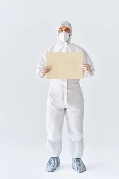 Médico en traje médico protector mostrando pancarta en blanco con espacio de copia para texto —  Fotos de Stock