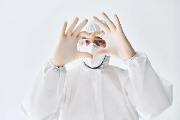 Medico rendendo simbolo di forma di cuore con le mani che indossano tuta medica protettiva — Foto Stock