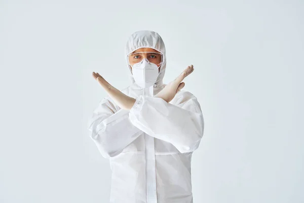 Doctor in protective medical suit showing stop sign on white background