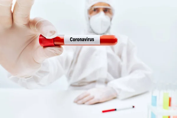 Доктор в захисному костюмі, що показує коронавірус заражений пробіркою зразка крові — стокове фото