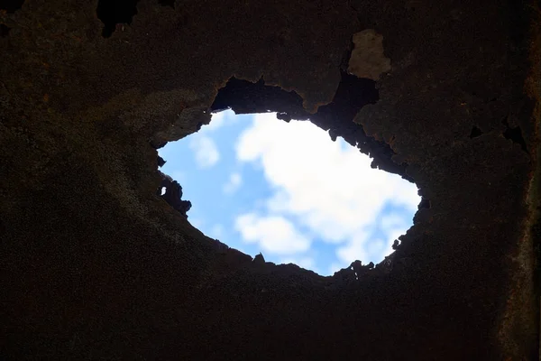 Blue sky through rusty hole — Stock Photo, Image