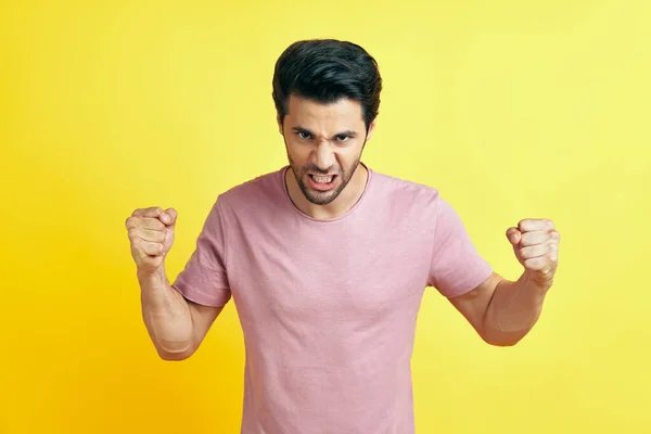 Wütender Mann mit erhobenen Fäusten auf gelbem Hintergrund — Stockfoto