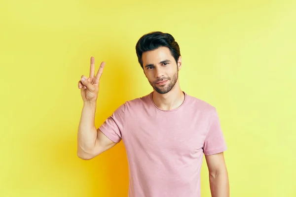 Joven hombre guapo mostrar signo de victoria sobre fondo amarillo — Foto de Stock