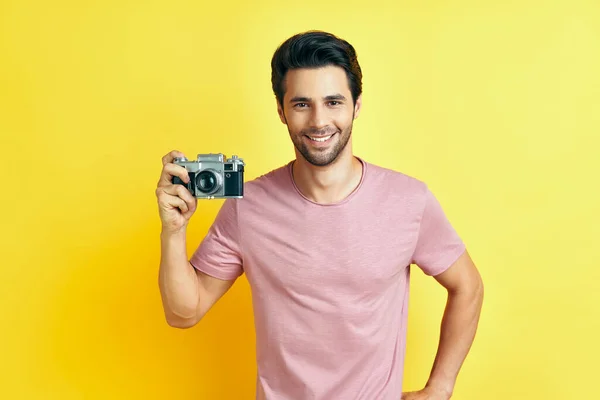 Hombre guapo sonriente con cámara retro sobre fondo amarillo — Foto de Stock