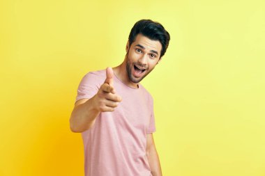 Mutlu gülümseyen adam seni işaret ediyor ve sarı arka planda kameraya bakıyor.