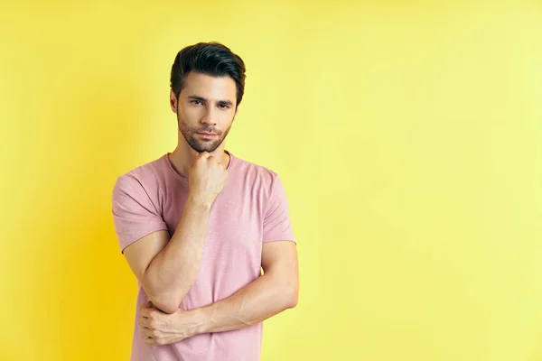 Junger, nachdenklicher Mann denkt und blickt in die Kamera mit Kopierraum, isoliert auf gelbem Hintergrund — Stockfoto