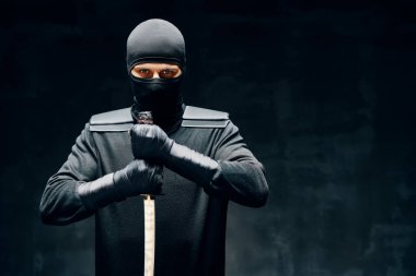 Siyah arka planda kılıçla savaşan bir ninja.