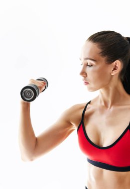 Spor kıyafetli bir kadın beyaz arka planda dambıllarla egzersiz yapıyor..