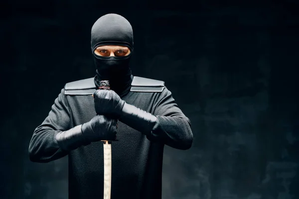Kämpfende Ninja posieren mit einem Schwert über schwarzem Hintergrund — Stockfoto