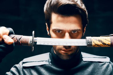 Kılıçla poz veren savaşçı adam.