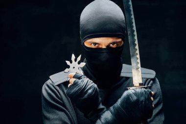Ninja samuray savaşçı kılıçlı ve shuriken siyah arka planda.