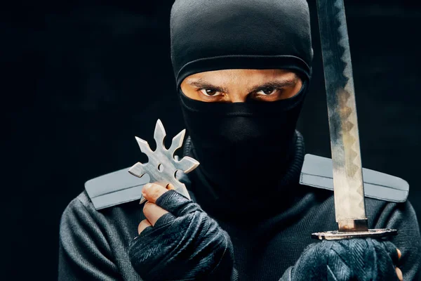 Ninja samuray savaşçı kılıçlı ve shuriken siyah arka planda.