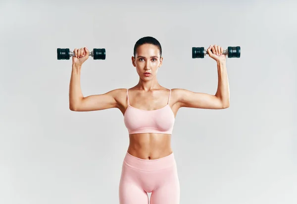 Deportiva mujer en ropa deportiva haciendo ejercicio con pesas sobre fondo blanco —  Fotos de Stock
