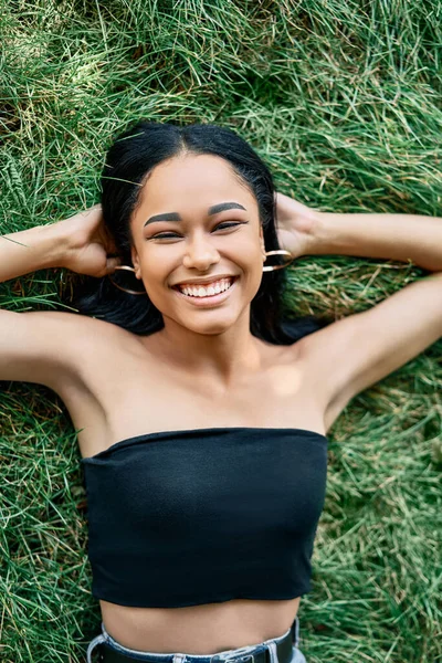 Top view portrait of pretty happy afro american woman relaxing on grass in park — Stock Photo, Image