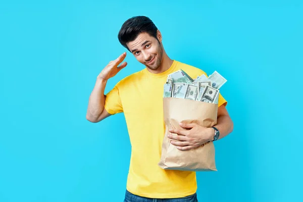 Snygg man saluterar innehav papperspåse full av högar med pengar — Stockfoto