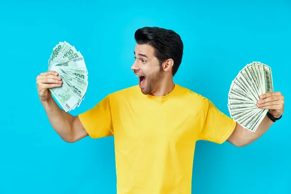 Glad upphetsad man håller pengar sedlar på blå bakgrund — Stockfoto