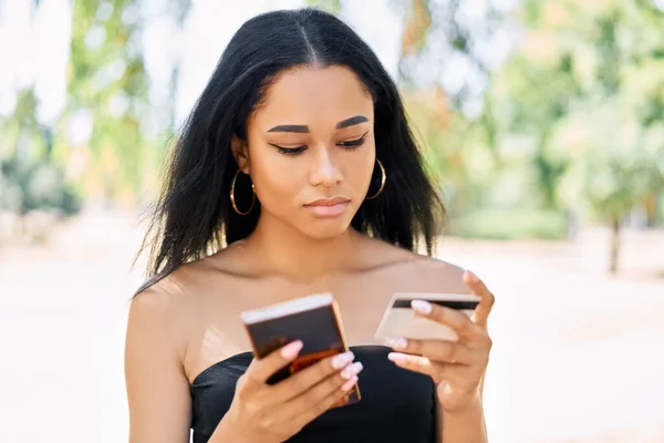 使用智能手机用信用卡在网上购物的非洲年轻妇女 — 图库照片
