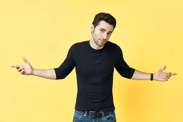 Confused young man dressed in black t-shirt have a doubt on yellow background — Stock Photo, Image
