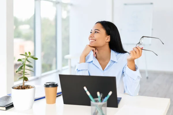 Sonriente mujer de negocios bonita posando en su escritorio en una oficina moderna y luminosa con espacio para copiar — Foto de Stock