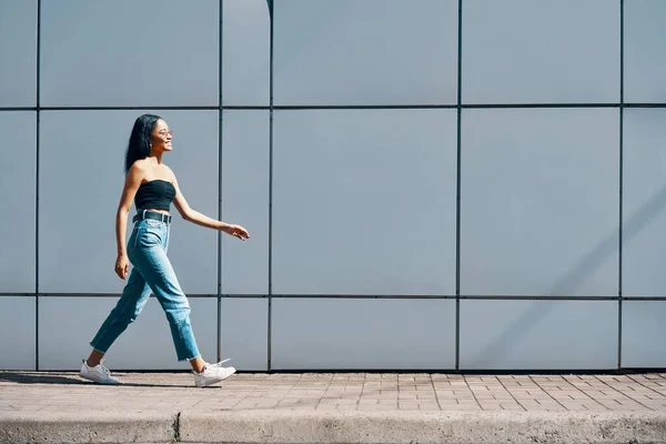 Moda mujer afroamericana de moda caminando a lo largo de la pared de la calle fondo urbano —  Fotos de Stock