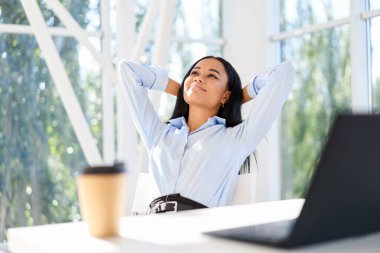 Çekici Afrikalı Amerikalı Amerikalı iş kadını modern ofiste dinleniyor ve boş zamanın tadını çıkarıyor.