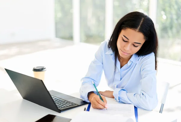 Empresaria afroamericana con laptop y papeles trabajando en oficina — Foto de Stock