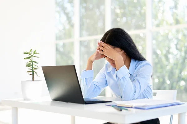 Vystresovaná unavená podnikatelka uzavřená tváří v tvář dvěma rukama sedí v moderní kanceláři — Stock fotografie