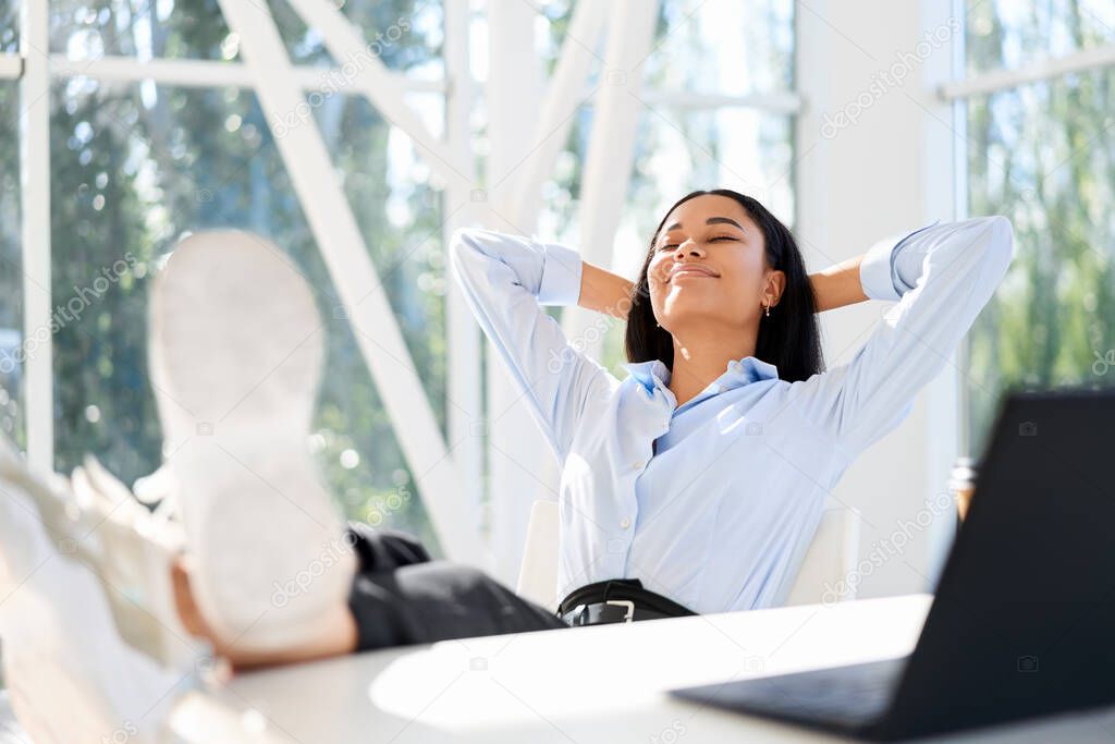 Attractive african american businesswoman resting in modern office enjoying free time