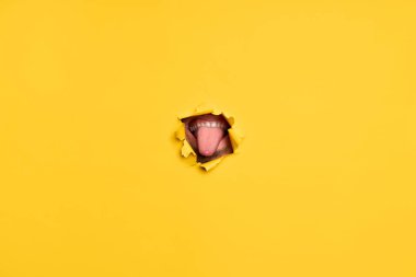 Yırtık sarı kağıtta insanların dilini gösteren yakın çekim. Eğlenceli konsept