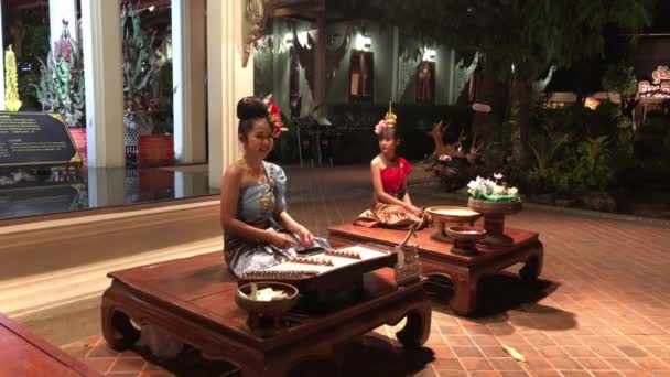 タイの伝統的な服を着た2人の女性の手持ち撮影 1つはチェンマイのレストランの外で木琴を演奏 — ストック動画