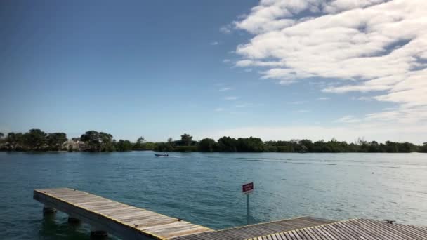 Prise de vue à la main d'une jetée en bois avec un bateau accélérant au loin 