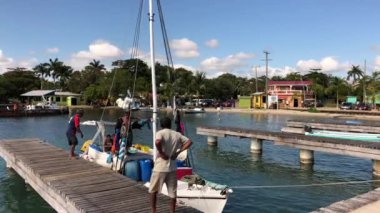 Placencia, Belize--Ocak 2018: Yerel balıkçılar Belize'nin Karayip kıyılarındaki Placencia adasında teknelerini dışarı çıkmaya hazırlanırken rüzgarla sallanan bir balıkçı teknesinin el yapımı fotoğrafı.