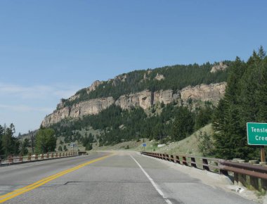 On Uyku, Wyoming Bighorn Dağları havzasında bir kasaba yaklaşan uzun kayalık granit kayalıklar etrafında Doğal yol dolambaçlı.