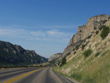Wyoming Bighorn Dağları ile kesme yol boyunca heybetli kayalık duvar nefes kesen görünümü, gökyüzünde güzel bulutlar ile.